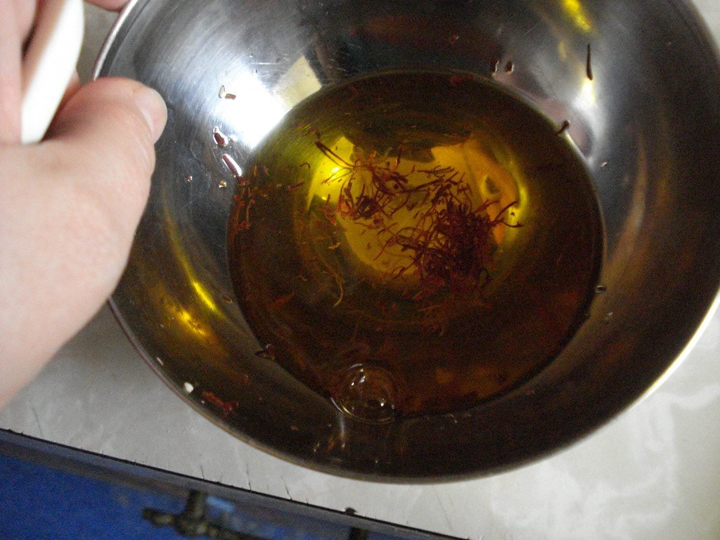 Filaments de safran colorant l'eau en jaune doré dans un bol, test pour vérifier un safran bien conservé